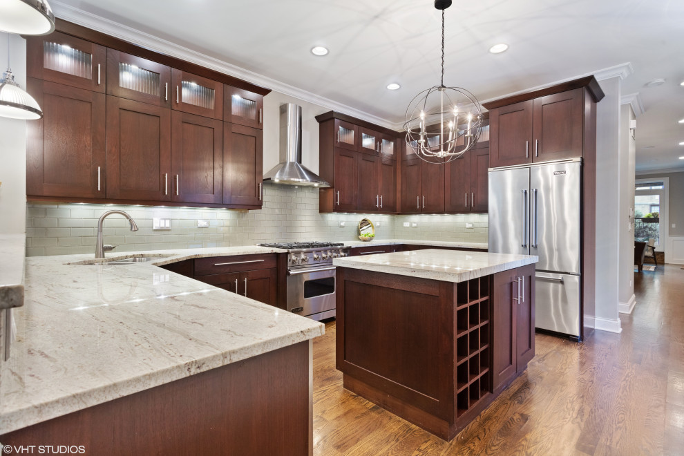 Example of a transitional u-shaped medium tone wood floor and brown floor open concept kitchen design in Chicago with an undermount sink, shaker cabinets, dark wood cabinets, granite countertops, gray backsplash, ceramic backsplash, stainless steel appliances and an island