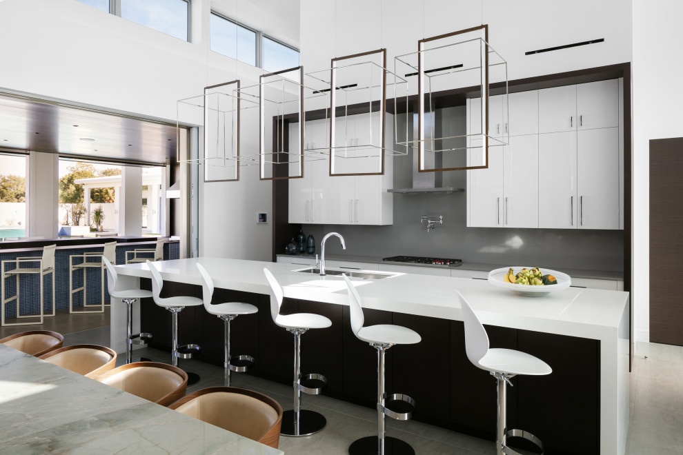 Bild på ett mycket stort funkis grå grått kök, med en dubbel diskho, släta luckor, vita skåp, bänkskiva i kvarts, grått stänkskydd, integrerade vitvaror, klinkergolv i porslin, en köksö och grått golv