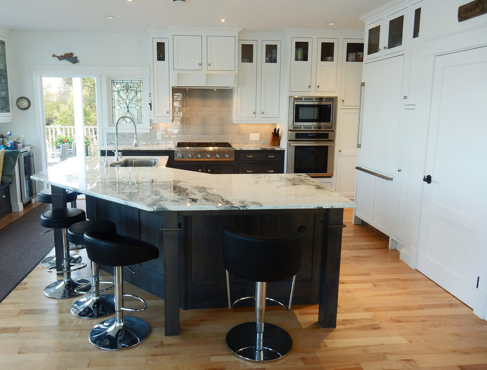 Mid-sized transitional l-shaped medium tone wood floor and brown floor open concept kitchen photo with an undermount sink, beaded inset cabinets, white cabinets, quartz countertops, gray backsplash, ceramic backsplash, stainless steel appliances, an island and white countertops