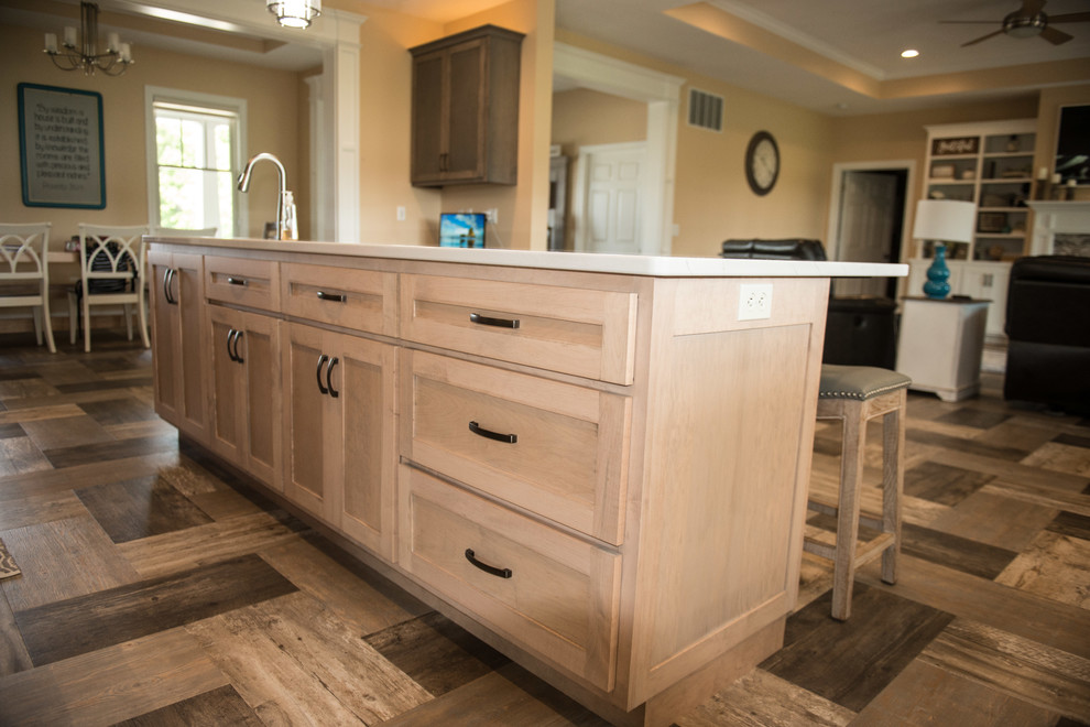 Example of a large transitional l-shaped vinyl floor and multicolored floor open concept kitchen design with a farmhouse sink, shaker cabinets, gray cabinets, quartz countertops, white backsplash, subway tile backsplash, stainless steel appliances, an island and white countertops