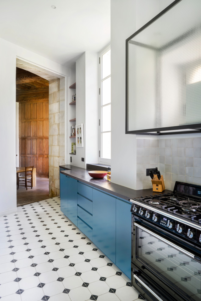 Offene Moderne Küche mit blauen Schränken, Küchenrückwand in Grau, schwarzen Elektrogeräten und grauer Arbeitsplatte in Sonstige
