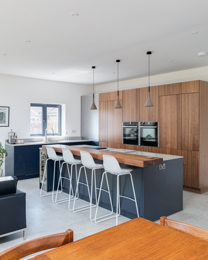 Inspiration for a mid-sized contemporary l-shaped open plan kitchen in Hertfordshire with a single-bowl sink, flat-panel cabinets, medium wood cabinets, concrete benchtops, stainless steel appliances, ceramic floors, with island, grey floor and grey benchtop.