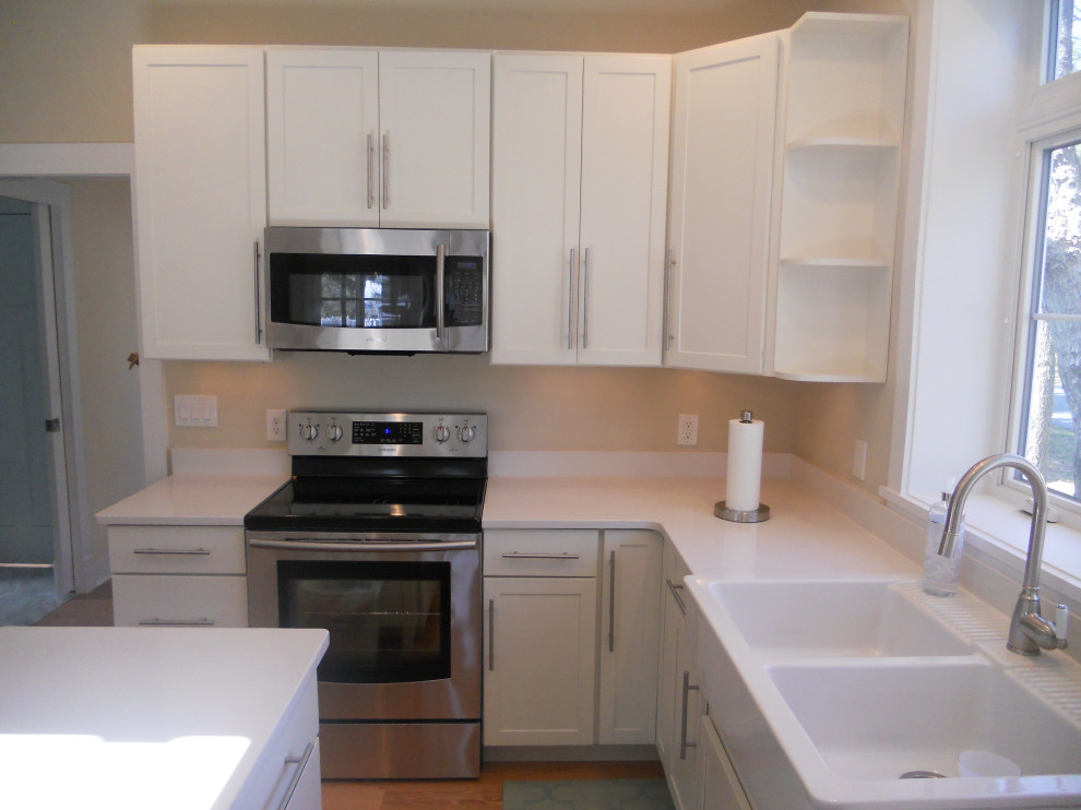 Inspiration for a mid-sized transitional l-shaped enclosed kitchen remodel with a double-bowl sink, shaker cabinets, white cabinets, quartz countertops, stainless steel appliances, an island and white countertops