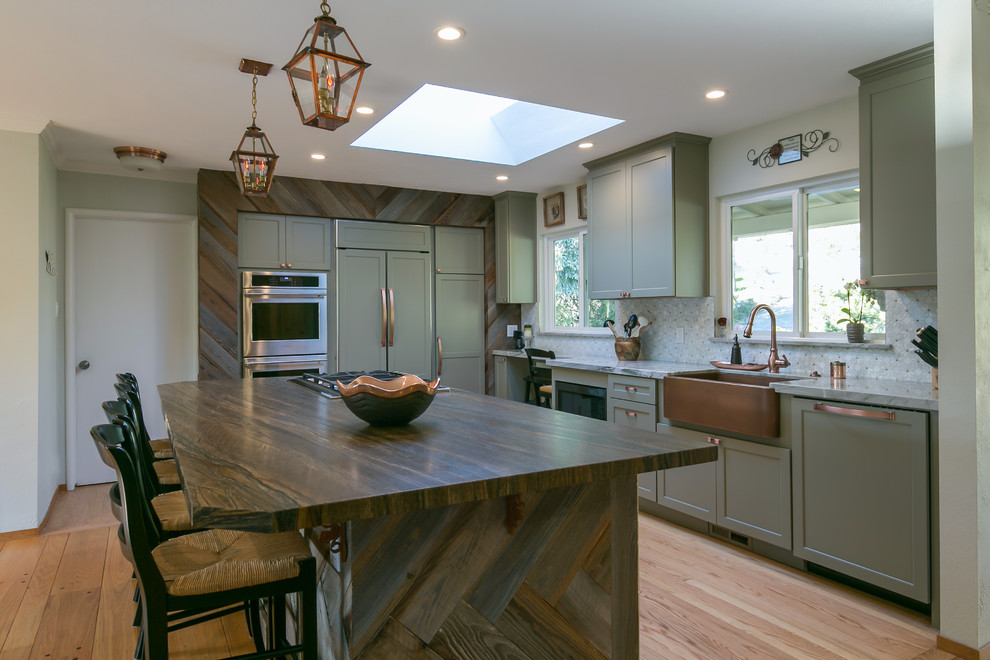 Inspiration for a mid-sized rustic l-shaped light wood floor and yellow floor open concept kitchen remodel in San Francisco with a farmhouse sink, shaker cabinets, green cabinets, quartzite countertops, multicolored backsplash, stainless steel appliances, an island and multicolored countertops