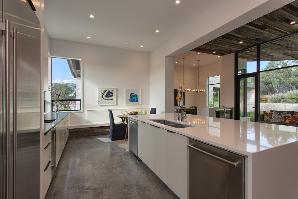 This is an example of a contemporary kitchen in Austin with stainless steel appliances, concrete floors and with island.