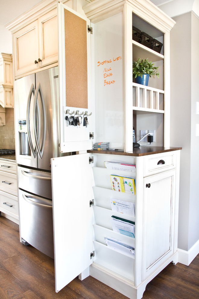 Photo of a large traditional kitchen in Vancouver with recessed-panel cabinets, white cabinets, wood benchtops and stainless steel appliances.