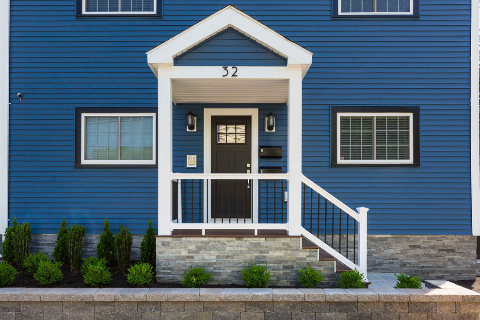This is an example of a modern two-storey blue apartment exterior in Boston with vinyl siding, a gable roof and a shingle roof.