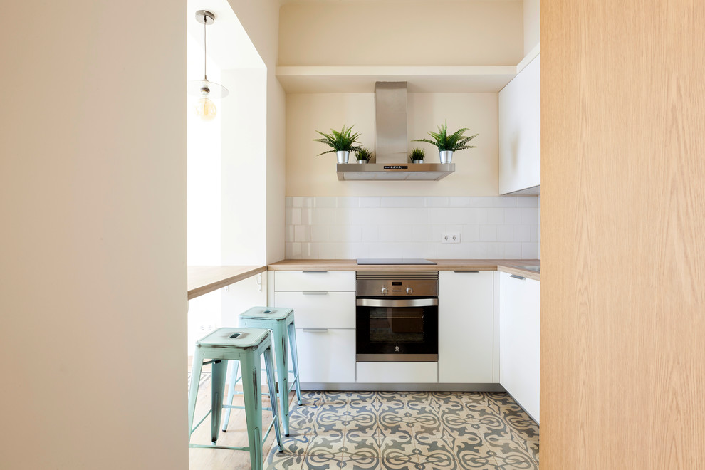 Inspiration for a mid-sized contemporary u-shaped open plan kitchen in Madrid with flat-panel cabinets, white cabinets, wood benchtops, white splashback, ceramic splashback, stainless steel appliances, ceramic floors, a peninsula and multi-coloured floor.