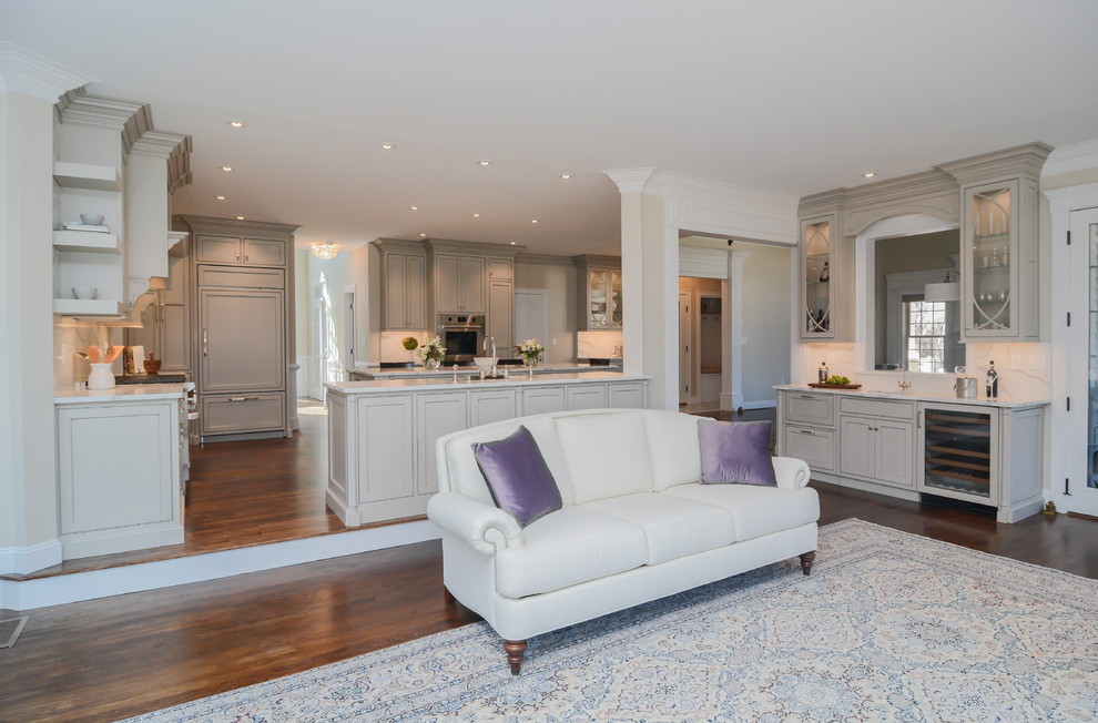 This is an example of an expansive traditional u-shaped open plan kitchen in Boston with a farmhouse sink, beaded inset cabinets, grey cabinets, quartz benchtops, white splashback, stone slab splashback, stainless steel appliances, medium hardwood floors, multiple islands and white benchtop.
