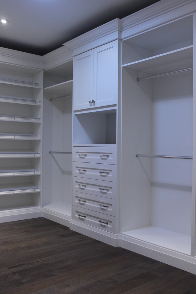 Design ideas for a mid-sized transitional gender-neutral walk-in wardrobe in Toronto with flat-panel cabinets, white cabinets and medium hardwood floors.