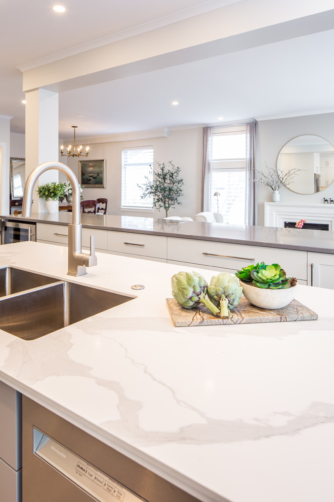 Inspiration for a small transitional l-shaped open plan kitchen in Vancouver with an undermount sink, shaker cabinets, white cabinets, quartz benchtops, white splashback, porcelain splashback, stainless steel appliances, light hardwood floors, with island, beige floor and white benchtop.