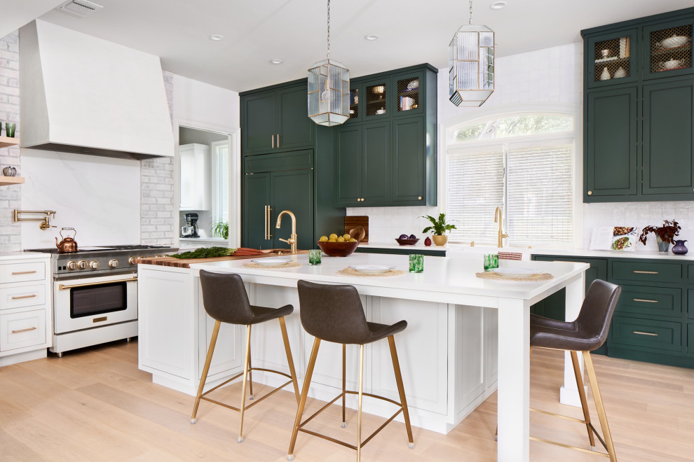 Example of a large transitional l-shaped medium tone wood floor kitchen design in Austin with a farmhouse sink, beaded inset cabinets, green cabinets, multicolored backsplash, paneled appliances, an island and white countertops