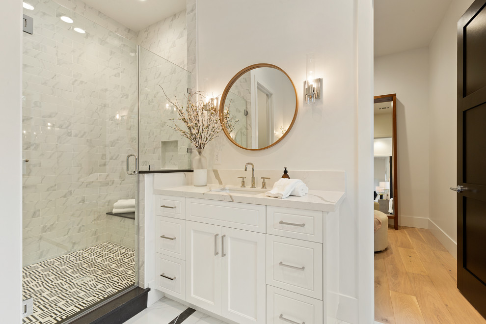 Idéer för funkis vitt en-suite badrum, med skåp i shakerstil, vita skåp, ett fristående badkar, en dusch i en alkov, vit kakel, marmorkakel, vita väggar, ett undermonterad handfat, bänkskiva i kvarts, vitt golv och dusch med gångjärnsdörr