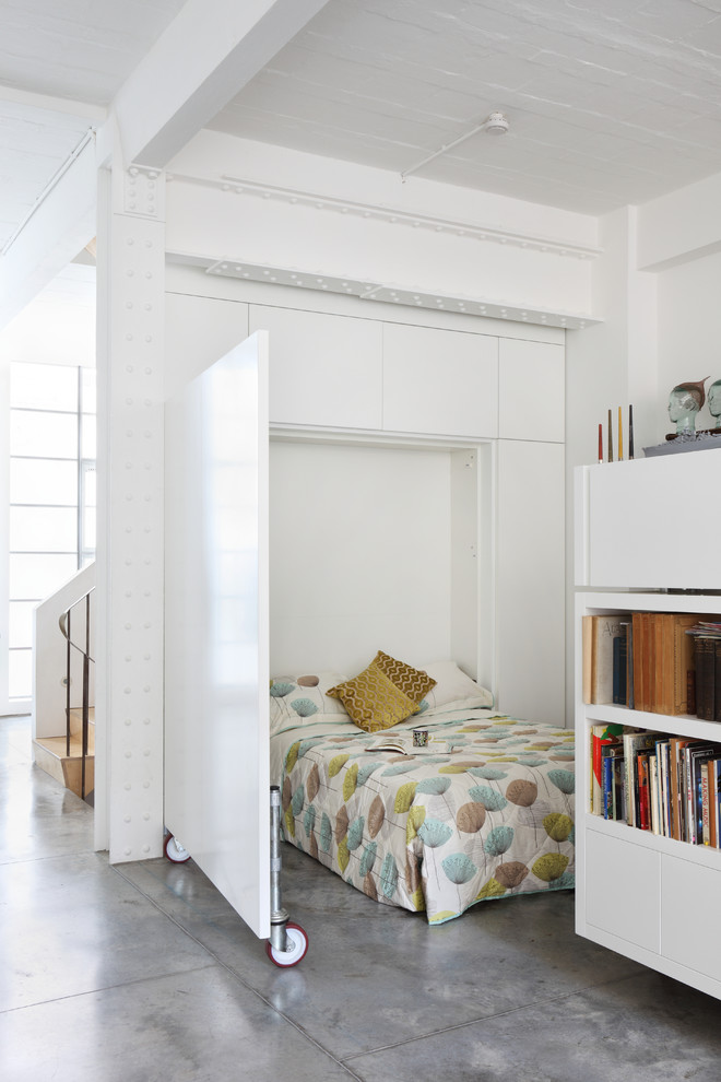 This is an example of an industrial bedroom in London with white walls and concrete floors.