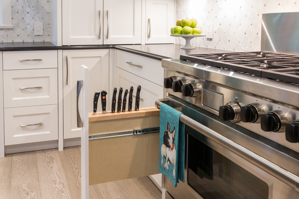 Large transitional l-shaped medium tone wood floor and beige floor eat-in kitchen photo in Vancouver with an undermount sink, shaker cabinets, white cabinets, granite countertops, gray backsplash, marble backsplash, stainless steel appliances, an island and black countertops