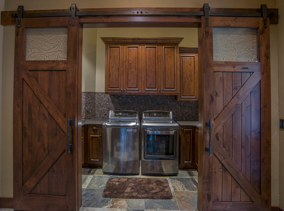 This is an example of a country u-shaped dedicated laundry room in Seattle with recessed-panel cabinets, dark wood cabinets, beige walls, slate floors and a side-by-side washer and dryer.