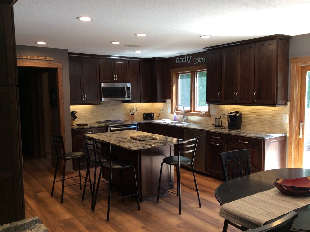 Large medium tone wood floor kitchen photo in Minneapolis with an undermount sink, dark wood cabinets, white backsplash, stainless steel appliances and an island
