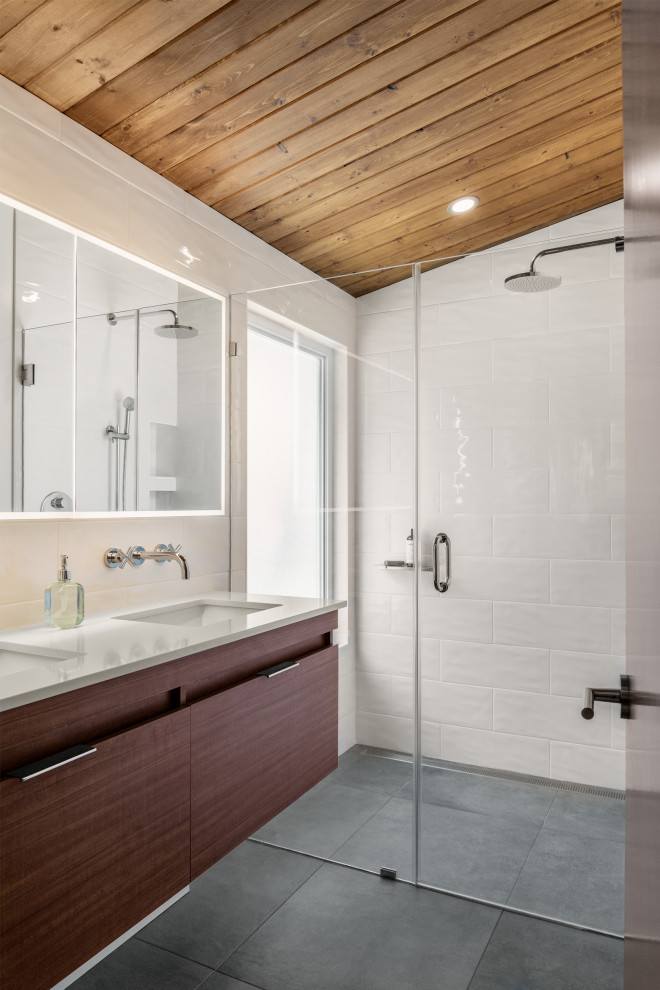 Пример оригинального дизайна: маленькая ванная комната в стиле ретро с плоскими фасадами, темными деревянными фасадами, угловой ванной, душем без бортиков, унитазом-моноблоком, белой плиткой, керамической плиткой, полом из сланца, душевой кабиной, врезной раковиной, столешницей из искусственного кварца, черным полом, душем с распашными дверями, белой столешницей, тумбой под две раковины, подвесной тумбой и деревянным потолком для на участке и в саду