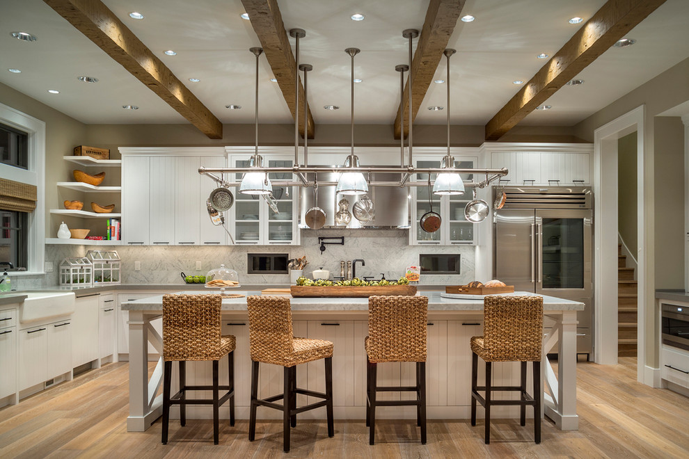 Photo of a country kitchen in San Francisco with a farmhouse sink, white cabinets, white splashback, stainless steel appliances, light hardwood floors and with island.