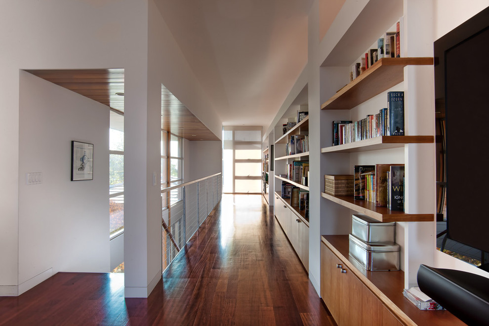 This is an example of a modern hallway in San Diego with white walls and dark hardwood floors.