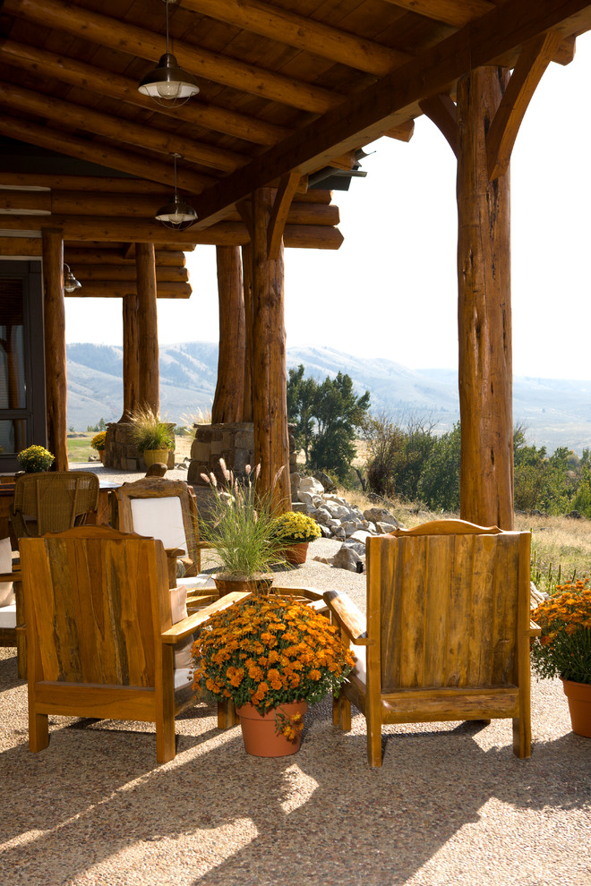 Example of a mountain style gravel patio design in Denver with a roof extension