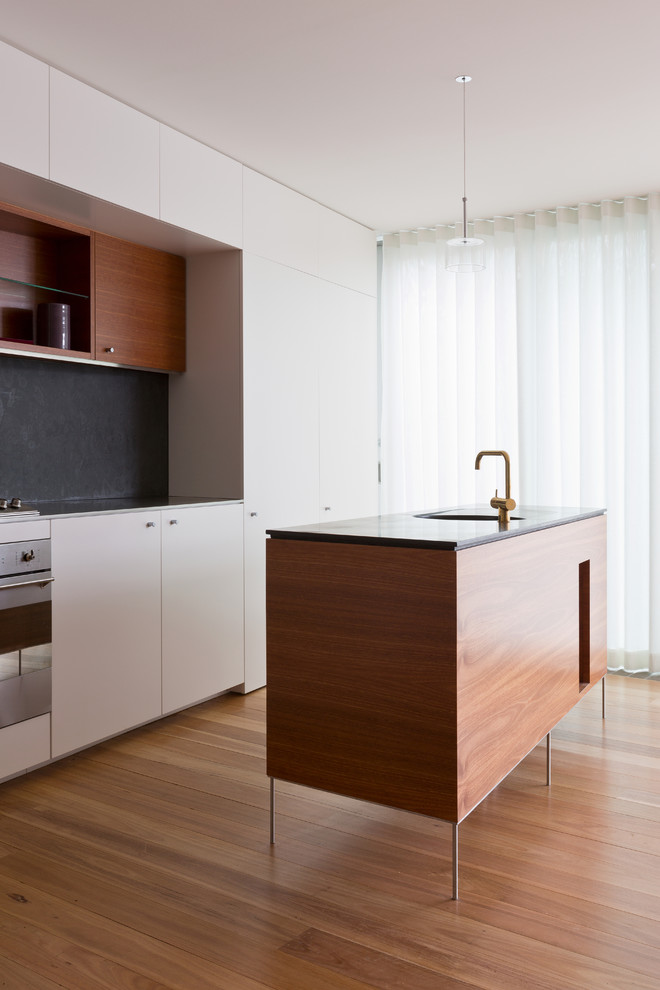 Design ideas for a contemporary kitchen in Sydney with flat-panel cabinets, white cabinets, medium hardwood floors and with island.