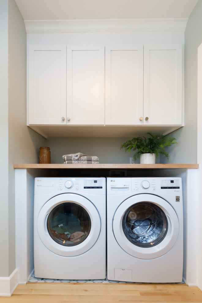 Inspiration för små klassiska linjära beige tvättstugor, med luckor med infälld panel, vita skåp, laminatbänkskiva, grå väggar, ljust trägolv och en tvättmaskin och torktumlare bredvid varandra