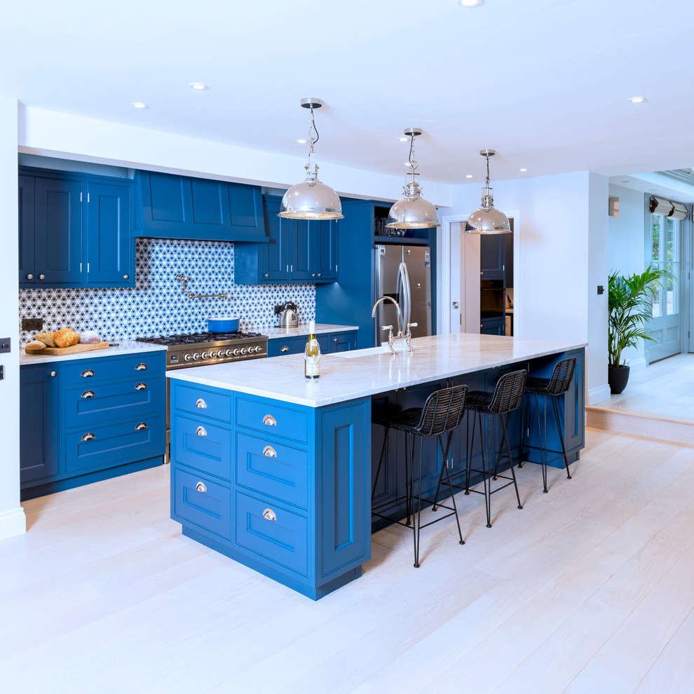 Inspiration for a large country galley open plan kitchen in Other with a farmhouse sink, recessed-panel cabinets, blue cabinets, blue splashback, stainless steel appliances, light hardwood floors, with island, beige floor, beige benchtop and marble benchtops.
