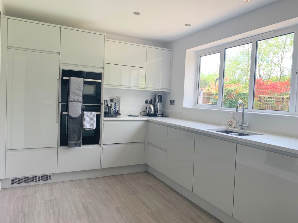 Mid-sized contemporary u-shaped separate kitchen in Buckinghamshire with an undermount sink, flat-panel cabinets, grey cabinets, quartzite benchtops, white splashback, panelled appliances, vinyl floors, no island and yellow benchtop.