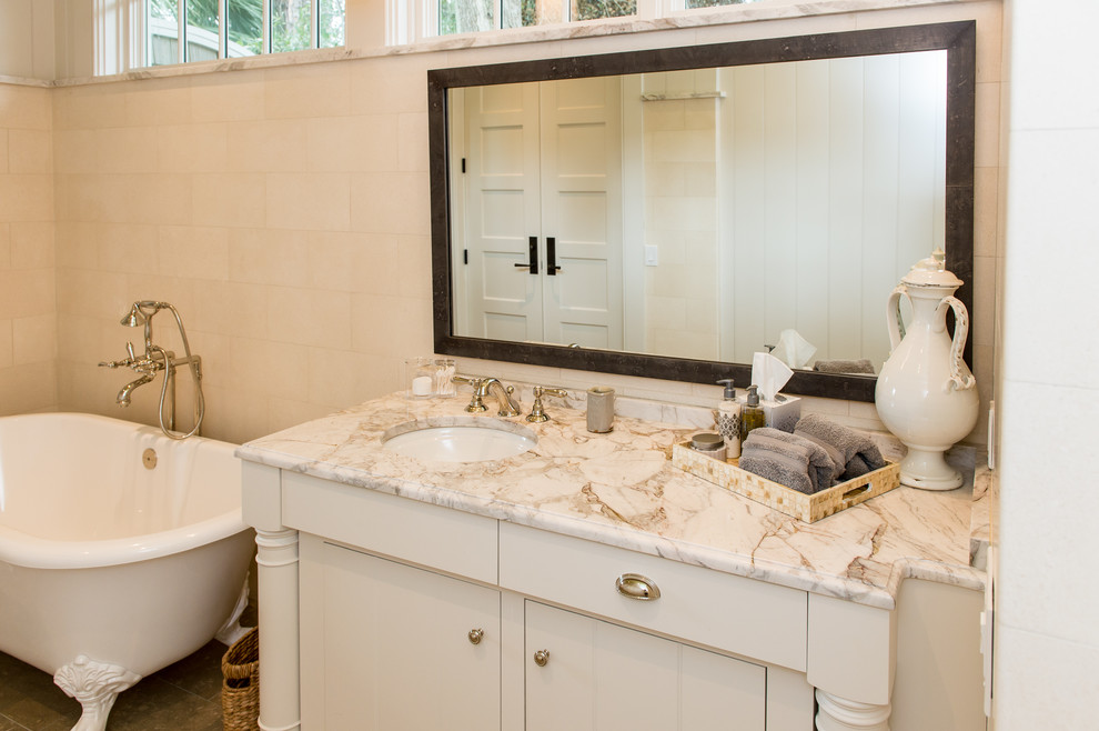 Photo of a large contemporary master bathroom in Charleston with furniture-like cabinets, light wood cabinets, a claw-foot tub, white tile, beige walls, limestone floors, an undermount sink, marble benchtops, a curbless shower and limestone.