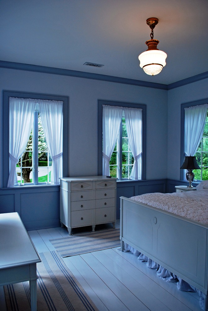 This is an example of a traditional bedroom in New York with blue walls and painted wood floors.