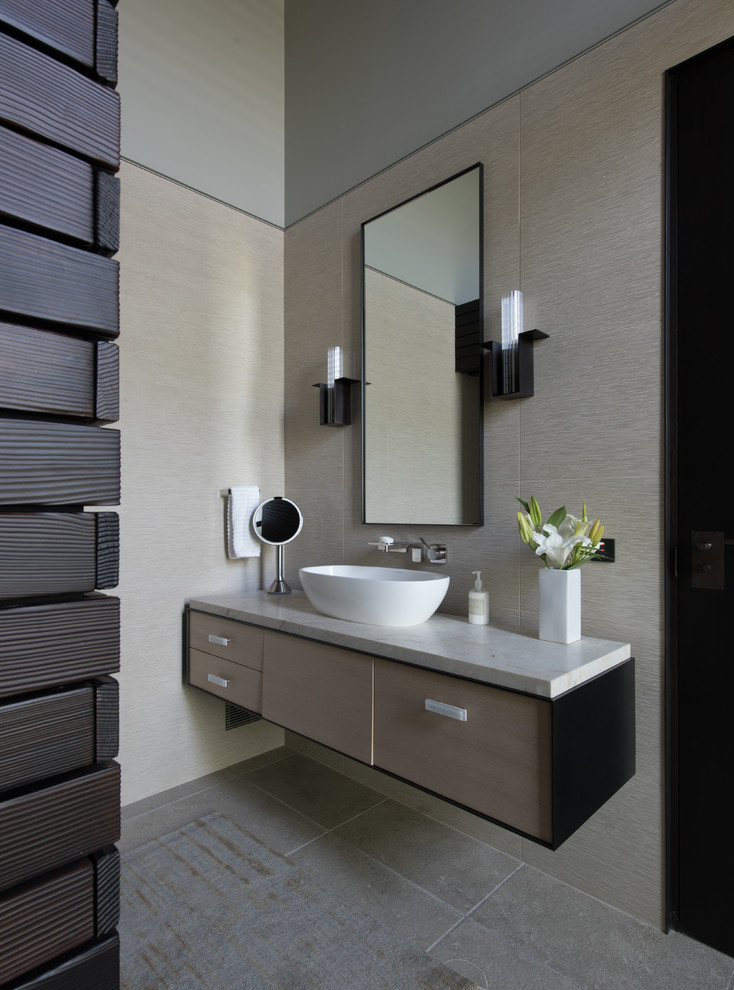 Design ideas for a mid-sized contemporary master bathroom in Seattle with flat-panel cabinets, brown cabinets, grey walls, a vessel sink, grey floor, grey benchtops, limestone floors and granite benchtops.