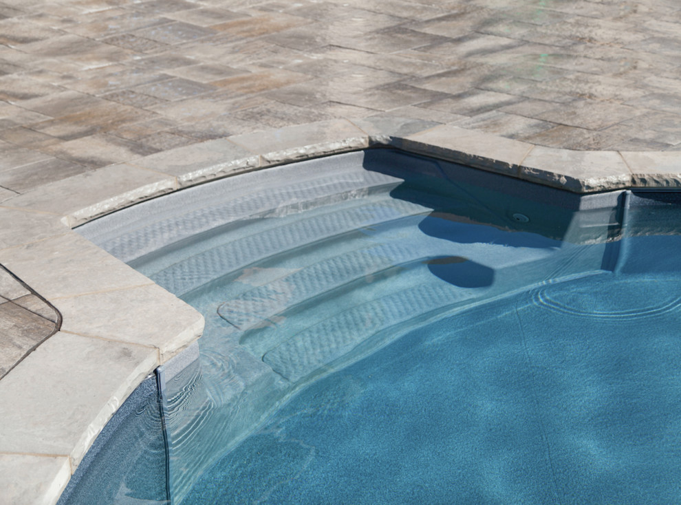 Example of a small transitional concrete paver and rectangular infinity pool design in Toronto
