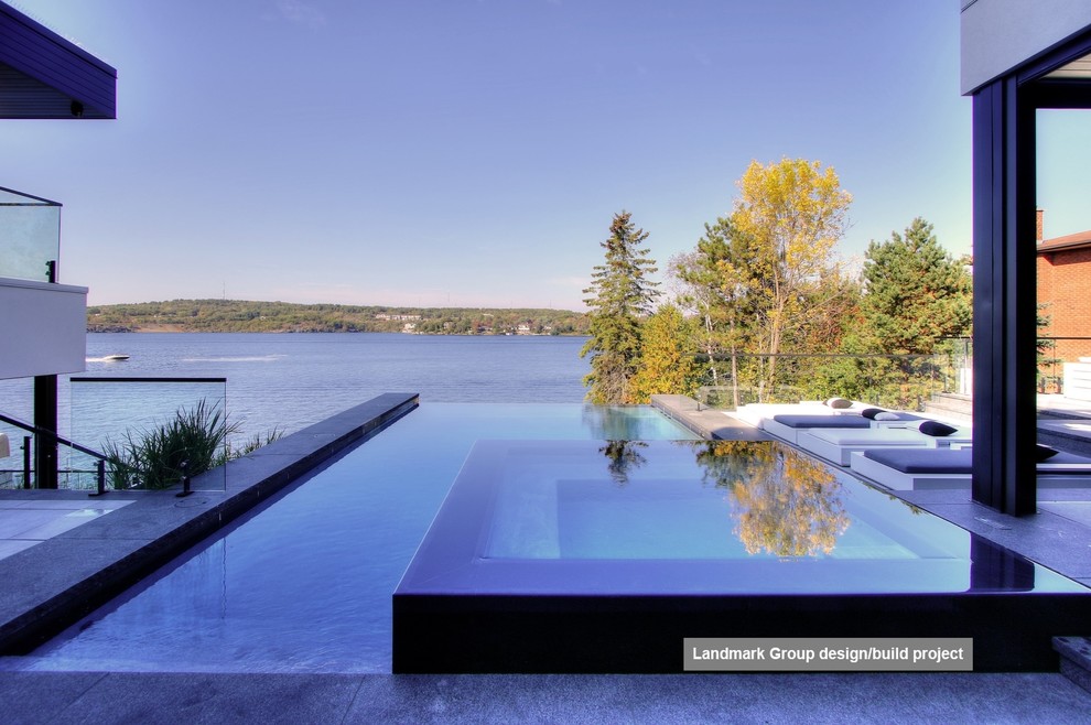This is an example of a mid-sized contemporary backyard rectangular infinity pool with a hot tub and natural stone pavers.