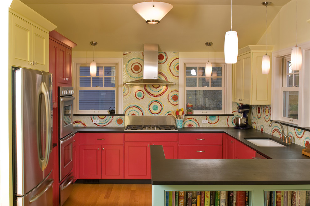 Photo of a contemporary u-shaped kitchen in Seattle with an undermount sink, recessed-panel cabinets, red cabinets, multi-coloured splashback, mosaic tile splashback and stainless steel appliances.
