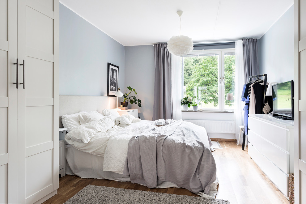 Mid-sized scandinavian master bedroom in Other with grey walls and light hardwood floors.