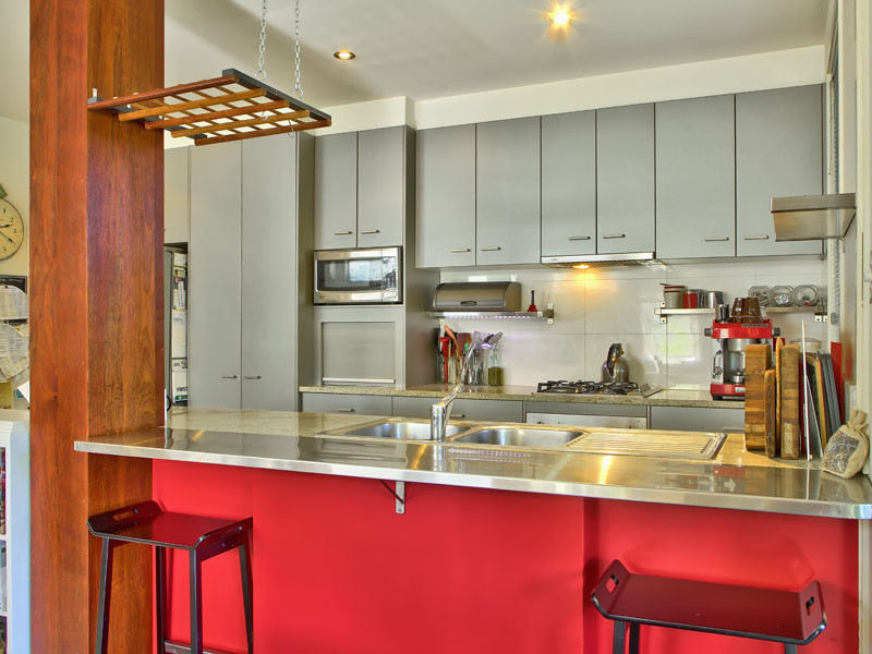 Mid-sized tropical u-shaped eat-in kitchen in Brisbane with a double-bowl sink, flat-panel cabinets, grey cabinets, solid surface benchtops, white splashback, ceramic splashback, stainless steel appliances, ceramic floors and with island.