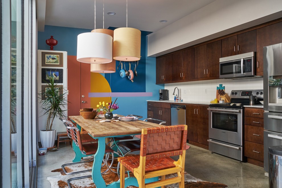 Eclectic single-wall eat-in kitchen in Los Angeles with flat-panel cabinets, dark wood cabinets, white splashback, stainless steel appliances, concrete floors, no island, grey floor and white benchtop.