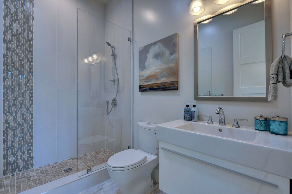 Photo of a small transitional 3/4 bathroom in San Francisco with white cabinets, ceramic tile, white walls, ceramic floors, solid surface benchtops, flat-panel cabinets, an alcove shower, a two-piece toilet, an integrated sink and a hinged shower door.