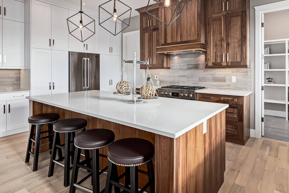 Inspiration for a mid-sized transitional galley light wood floor eat-in kitchen remodel in Calgary with recessed-panel cabinets, medium tone wood cabinets, quartz countertops, gray backsplash, ceramic backsplash, stainless steel appliances and an island