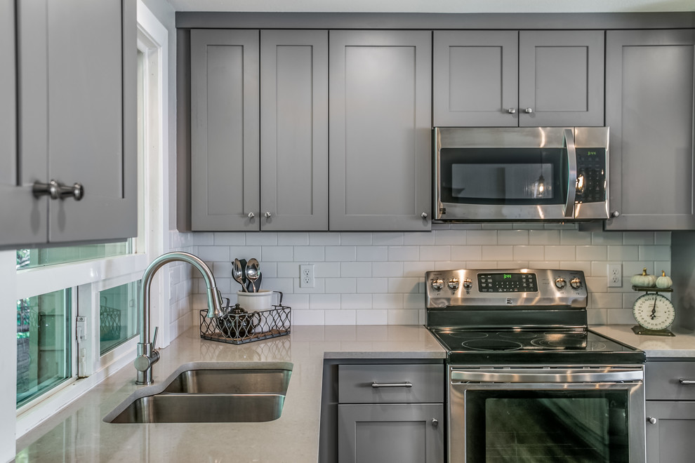 Inspiration for a mid-sized transitional l-shaped vinyl floor and brown floor eat-in kitchen remodel in Seattle with an undermount sink, shaker cabinets, gray cabinets, quartz countertops, white backsplash, subway tile backsplash, stainless steel appliances and an island