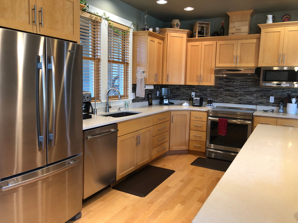 Mid-sized transitional l-shaped medium tone wood floor open concept kitchen photo with an undermount sink, flat-panel cabinets, light wood cabinets, quartz countertops, multicolored backsplash, ceramic backsplash, stainless steel appliances, an island and white countertops