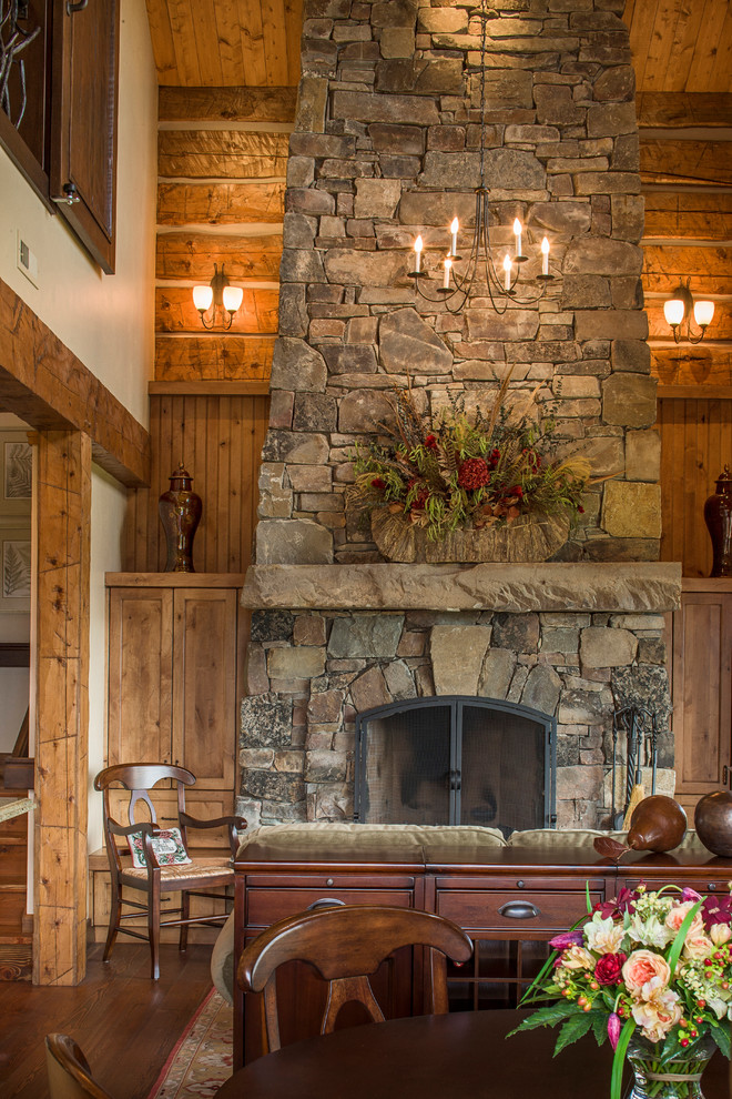 Photo of a mid-sized country open plan dining in Other with beige walls, dark hardwood floors, a standard fireplace, a stone fireplace surround and brown floor.