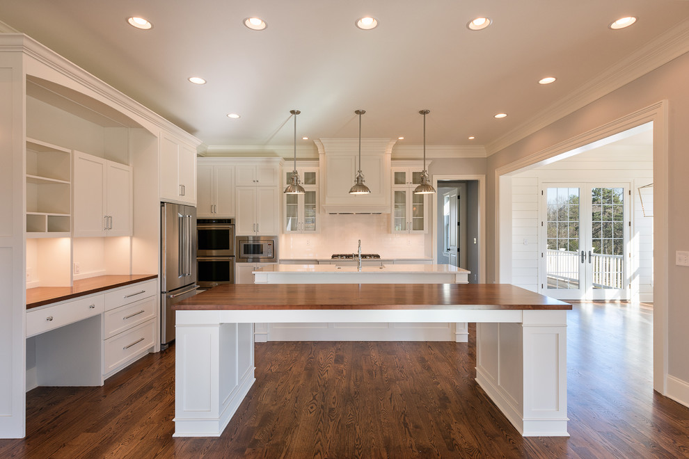 Mid-sized transitional l-shaped dark wood floor and brown floor open concept kitchen photo with a farmhouse sink, shaker cabinets, white cabinets, granite countertops, stainless steel appliances and two islands