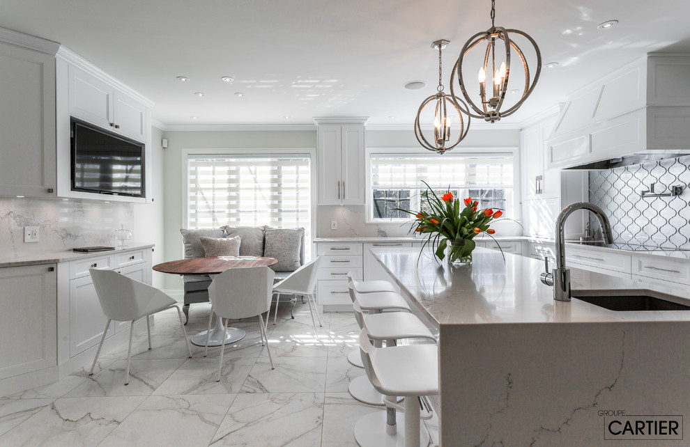 Example of a huge transitional l-shaped marble floor eat-in kitchen design in Montreal with an undermount sink, shaker cabinets, white cabinets, quartzite countertops, gray backsplash, glass tile backsplash, paneled appliances and an island