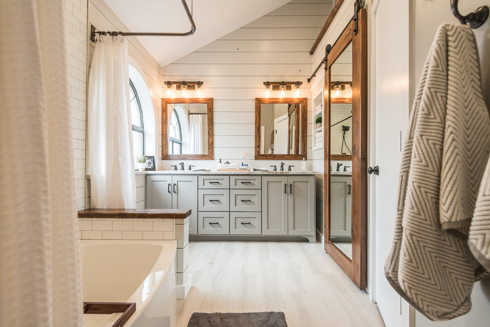 Mid-sized country master bathroom in Dallas with grey cabinets, an alcove tub, a shower/bathtub combo, a one-piece toilet, gray tile, white tile, grey walls, porcelain floors, an undermount sink, granite benchtops, subway tile and a shower curtain.