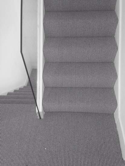 Design ideas for a transitional carpeted u-shaped staircase in London with carpet risers and wood railing.