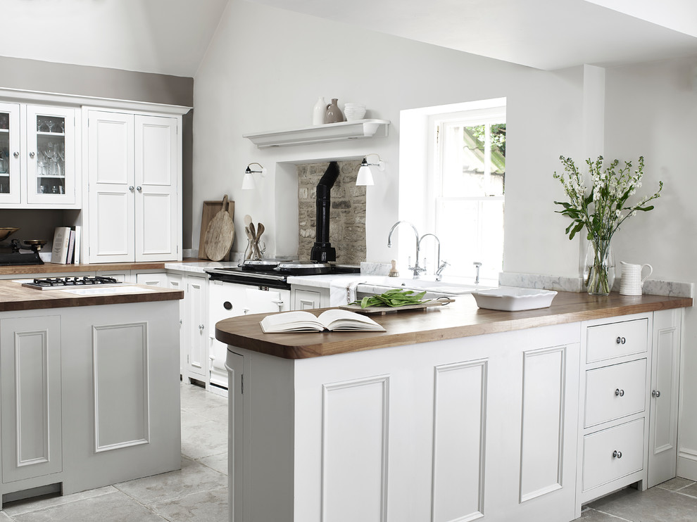 Design ideas for a mid-sized traditional single-wall kitchen in London with a farmhouse sink, shaker cabinets, grey cabinets, wood benchtops, brick splashback, stainless steel appliances, with island and grey floor.
