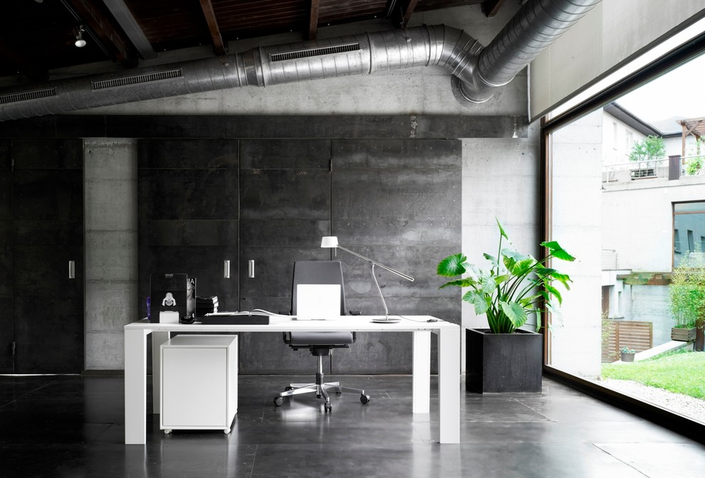 Photo of a mid-sized industrial study room in Other with black walls, no fireplace and a freestanding desk.