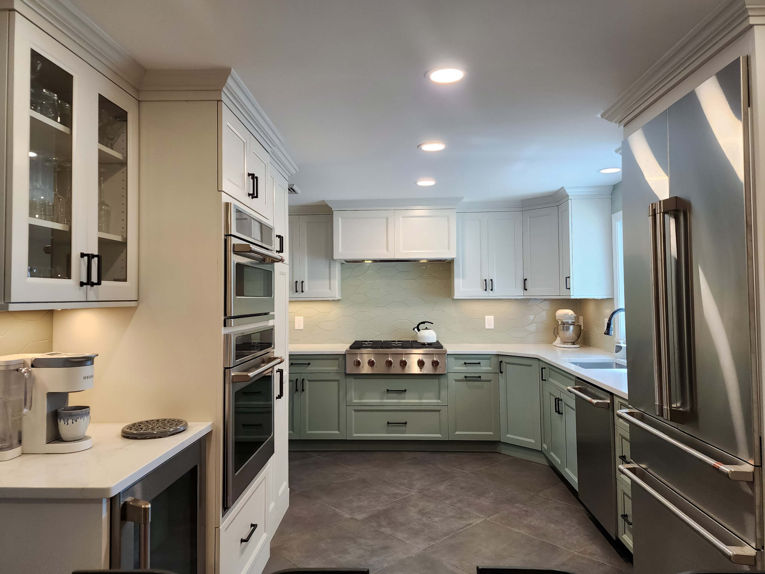 Example of a mid-sized transitional l-shaped porcelain tile and brown floor kitchen design in Boston with an undermount sink, shaker cabinets, white cabinets, quartz countertops, gray backsplash, cera